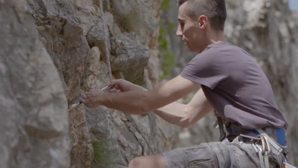 Ein männlicher Bergsteiger klettert einen Felsen hinauf — Stockvideo