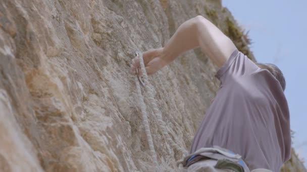 Een mannelijke bergbeklimmer klimt op een rots — Stockvideo