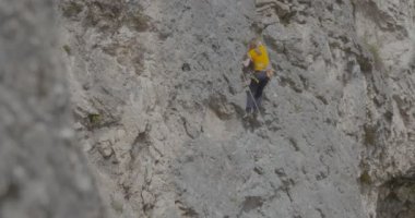 Bir kadın dağcı bir kayayı tırmanıyor