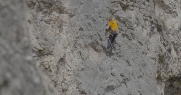 A female rock climber climbs up a rock — Stock Video