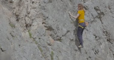 Bir kadın dağcı bir kayayı tırmanıyor