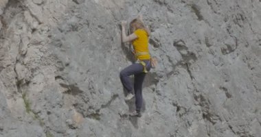 Bir kadın dağcı bir kayayı tırmanıyor