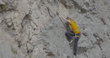 Bir kadın dağcı bir kayayı tırmanıyor