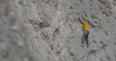 Bir kadın dağcı bir kayayı tırmanıyor