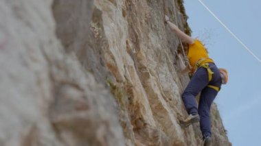 Bir kadın dağcı bir kayayı tırmanıyor