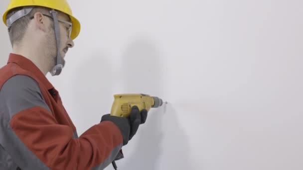 Werknemer met behulp van een machine te boren en het boren van gat in de muur — Stockvideo