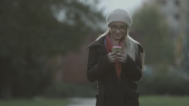Mulher sms mensagens de texto no telefone inteligente no parque na cidade — Vídeo de Stock