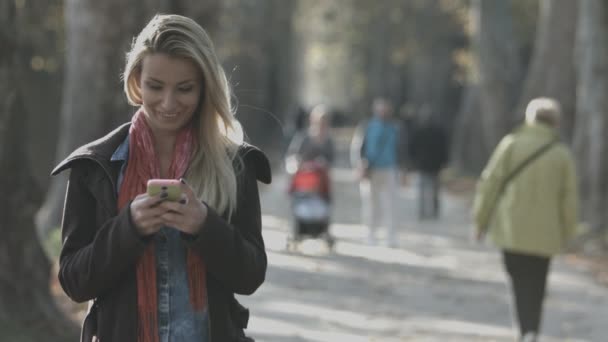 Frau schreibt SMS auf Smartphone im Park in der Stadt — Stockvideo