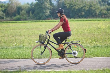 Şapkalı bir parkta Bisiklete binmek bir çekici genç kadın. Aktif insanlar. Açık havada