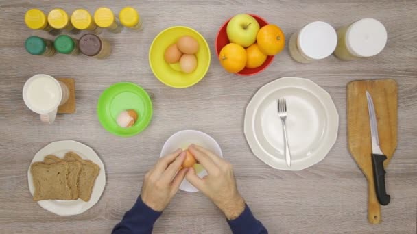 Чоловік робить яйця на кухні — стокове відео