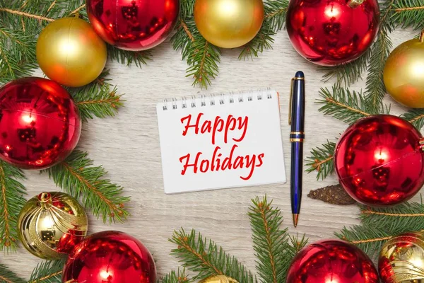 Página de caderno com texto HAPPY HOLIDAYS com decoração em mesa de escritório de madeira — Fotografia de Stock