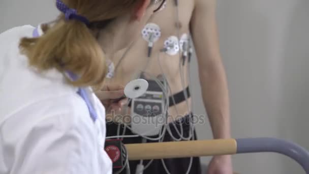 Vrouwelijke arts controleert de voortgang van de jonge man Ecg — Stockvideo