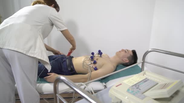 Жінка-лікар стежить за прогресом молодого чоловіка ECG — стокове відео