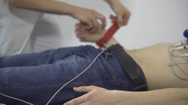 Female doctor monitors the progress of the a young man ECG — Stock Video