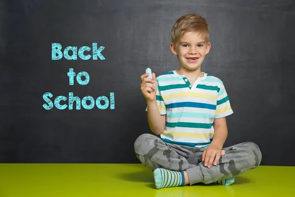 Niño con tiza y tablero escolar con texto VOLVER A ESCUELA —  Fotos de Stock