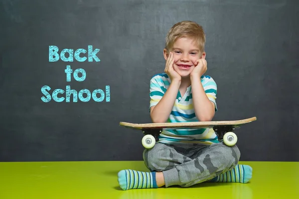 Niño con monopatín y tablero escolar con texto VOLVER A ESCUELA —  Fotos de Stock