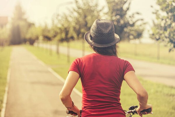 Back view of young woman riding on bike 