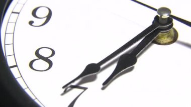 Beyaz duvar saatleri çalışıyor. Saatin hareket eden elleri. Işıklar saatin kollarını oynatıyor. Sığ alan derinliği