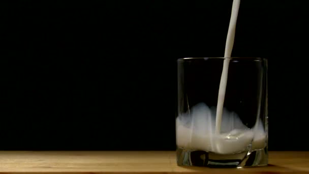 グラスに牛乳を入れる 黒の背景 — ストック動画