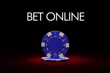 Kırmızı keçeli masa üzerindeki mavi poker çipinin yakın plan fişi ve arka plandaki leke ışığı ile yakın plan 