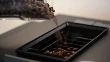 Taze kahve çekirdeklerini yavaşça modern kahve makinesine ekleyin..