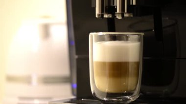 Kadın elinin modern kahve makinesinden temiz bir bardak macchiato kahvesi içtiği yakın plan fotoğraf.. 
