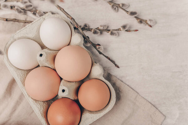 Easter eggs in a box with willow branches on grey backgroun