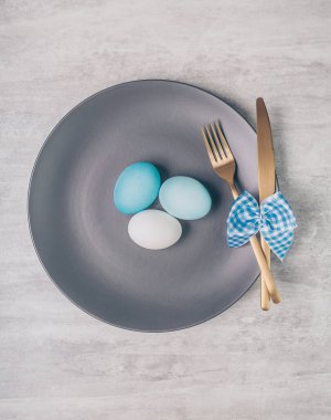 Gri plakalı Paskalya masası ve gri ahşap masadaki mavi yumurtalar.. 
