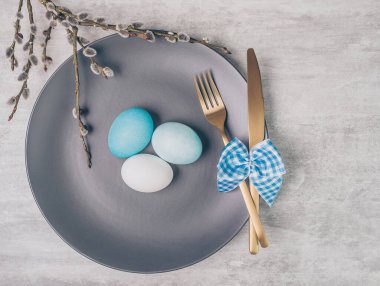 Gri plakalı Paskalya masası ve gri ahşap masadaki mavi yumurtalar.. 