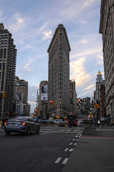 Persone e veicoli sulla strada di punta del mattino intorno a Flatiron Building durante l'alba a New York — Foto Stock