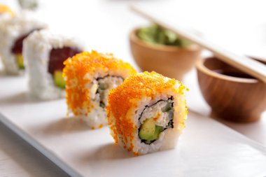California roll ve ton avokado beyaz plaka üzerinde rulo