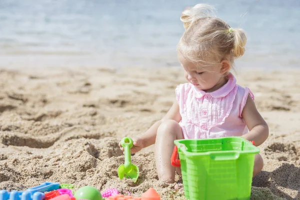 Κορίτσι παίζει παιχνίδια άμμου στην παραλία — Φωτογραφία Αρχείου