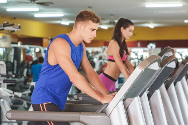 Spor salonunda koşu bandı üzerinde güzel kadın adamla — Stok fotoğraf