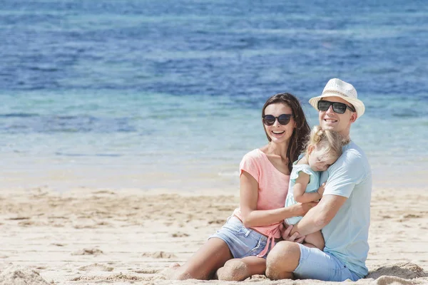 Familjen sitter tillsammans på stranden — Stockfoto