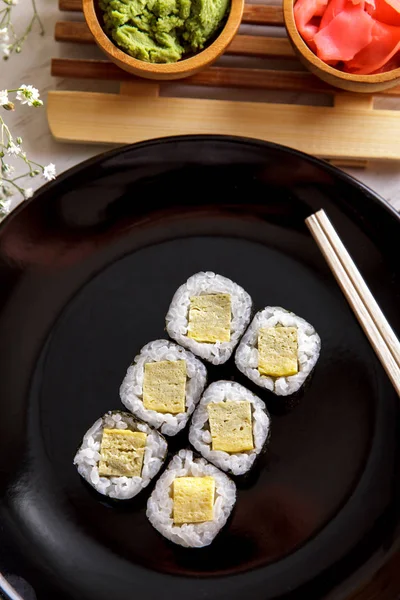 Japanisches Essen Tamago Maki Sushi auf schwarzem Teller — Stockfoto