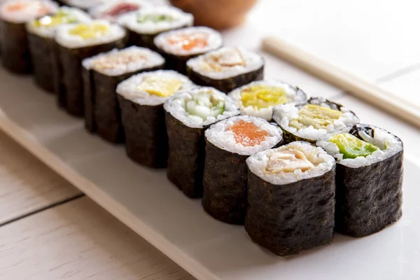 Comida japonesa mini bandeja de sushi maki sobre mesa de madera blanca — Foto de Stock