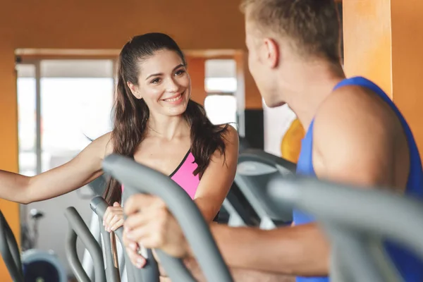 Mulher com parceiro exercitando em máquinas de fitness — Fotografia de Stock