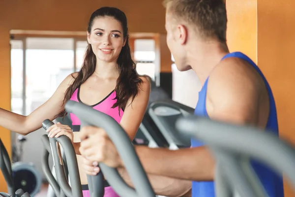 Mulher com parceiro exercitando em máquinas de fitness — Fotografia de Stock