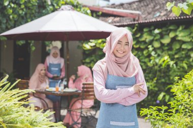 kafe önünde duran işletme sahibi