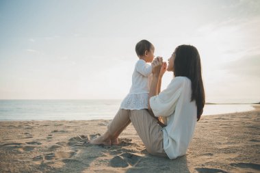 Anne ve bebek günbatımında sevinç