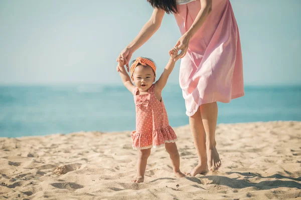 Mère enseigne à sa fille marche sur la plage — Photo