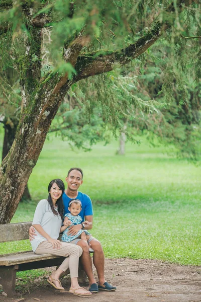 Zittend op een bankje in het park en gelukkige familie — Stockfoto