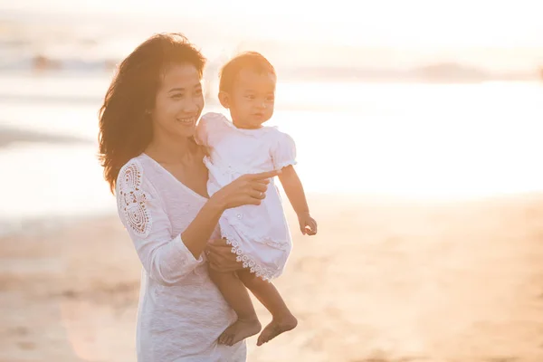 Retrato de mãe e bebê na praia ao pôr do sol — Fotografia de Stock