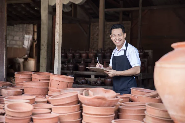 Laki-laki tukang periuk memeriksa produk tembikarnya — Stok Foto