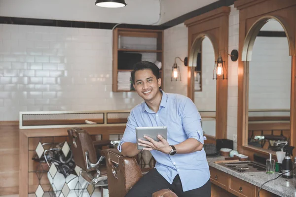 Jonge Kapper deskundige glimlachend kijken camera in de barbershop — Stockfoto