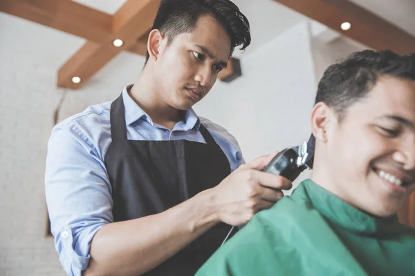 Парикмахерская делает стрижку привлекательного мужчины в парикмахерской — стоковое фото