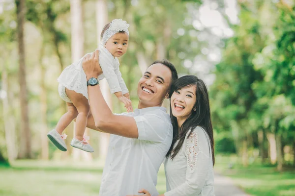 Orang tua berpakaian putih berjalan dengan putri bayi mereka — Stok Foto