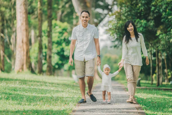 Far, mor och baby promenad längs parken — Stockfoto