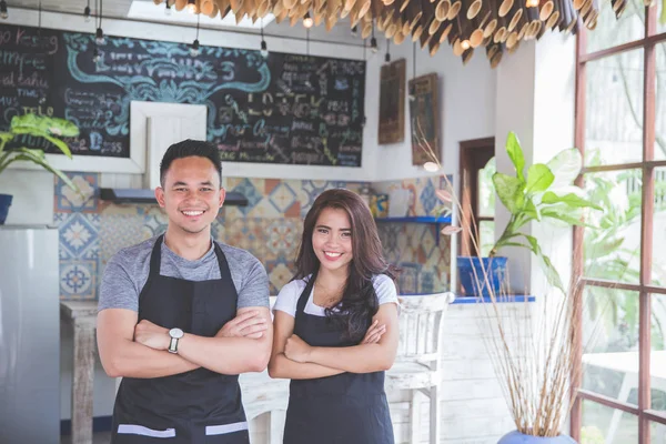 Camarera masculina y femenina de pie con los brazos cruzados en el café — Foto de Stock