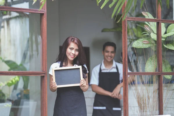 Serveerster permanent aan de voorzijde van een café uit te nodigen mensen te komen — Stockfoto